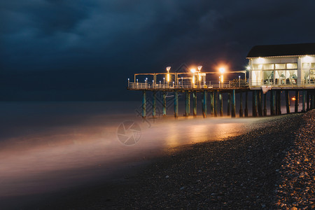 海滩暴风天气和长期露的夜晚在海上建造灯光照明设施以及反射欧洲风暴图片