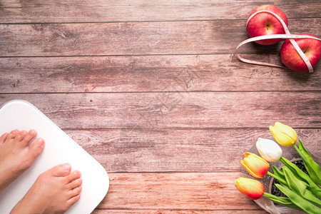 措施妇女脚站着规模饮食红苹果与木质背景健康和生活概念的测量胶带捆绑在一起木质背景上有女双脚按比例表站立和饮食红苹果男人女士图片