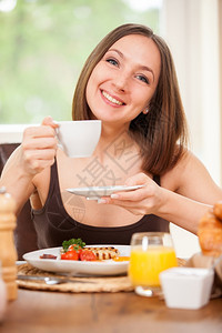 现代的女士年轻caucasian女在家吃早餐的照片可口图片
