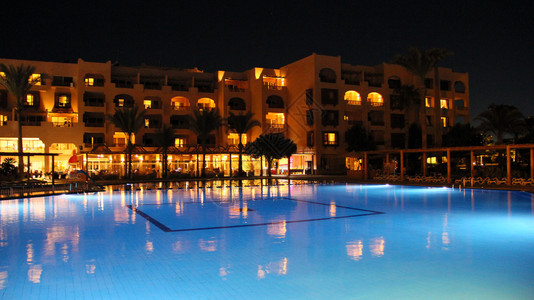 水上公园屋休息游泳池和假日夜间酒店人们晚上在游泳池附近放松晚上酒店的灯光在晚上游泳池水中反射图片