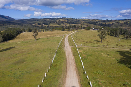 区域天空在绿色农业田中看到一条有白色围栏标志的泥土道路在绿色农业田中栅栏图片