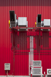 HVAC空调系统各种设备在工业建筑外的红色金属板墙壁上垂直架立高压气体空调系统的各种设备框架扇子加热图片