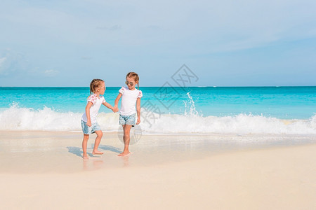夏日度假时海滩上可爱的小女孩与绿海和白沙一起在滩上玩得开心美丽的小女孩在海滩上很快乐人们孩子海岸线图片