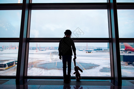 旅行李小女孩带着兔子玩具在大窗户附近的机场等待登小女孩在大窗户附近的机场等待登童年图片