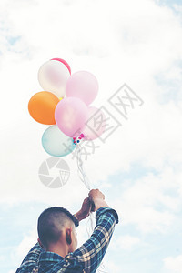 男人快乐的年轻嬉皮士在草原上拿着多彩气球的欢快年轻嬉皮士在草地享受生活和快乐的清楚男图片