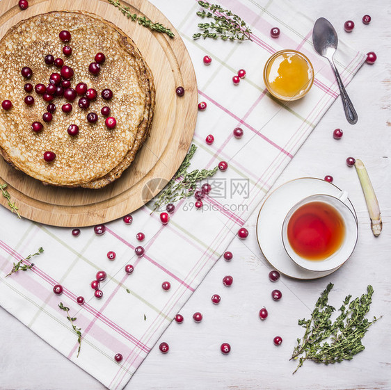 切割酸果蔓煎饼加蜂蜜和红莓茶杯加百香和勺子餐巾纸板上贴着铁制背景最深的木质餐巾纸早图片