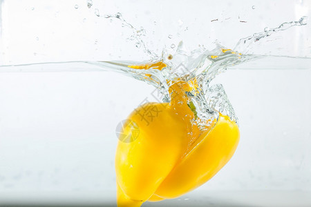 烹饪甜辣椒在水中喷洒黄色的白背景甜辣椒是一种不有机的湿图片