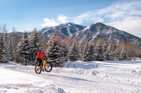 红色的白冰肥胖自行车也叫肥的自行车或重大轮上的赛车青少年骑着自行车穿过背景中的雪山图片