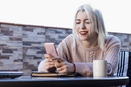 女士杯子在露天休息时持有智能手机的褐发女人肖像尽管图片