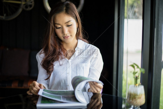 工作杯子成人亚裔女在咖啡店微笑并阅读一本放松的书图片