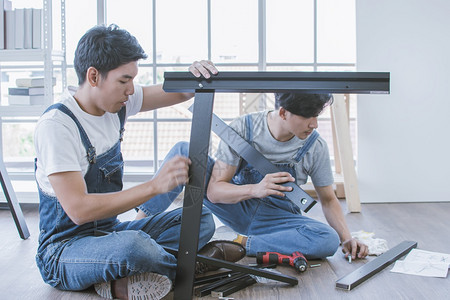 两个亚洲英俊男子正在一起帮忙做家具组装工作男人行业修理工图片