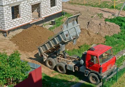 卡车和房子的是用白砖建造的自卸车把沙子带到建筑物上自卸车靠近正在建造的房子翻斗车靠近正在建造的房子卡车和是用白砖建造的自卸车将沙图片