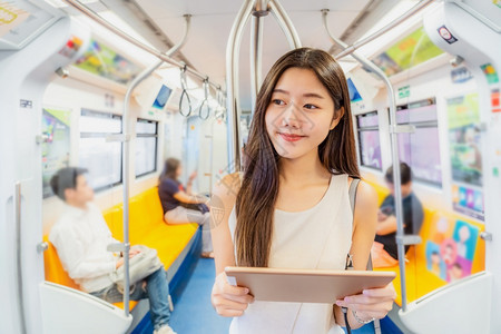年轻的多媒体乘坐地铁火车技术平板机的亚洲青年女乘客在大城市japanesechinese朝韩生活方式和日常commuter及交通图片