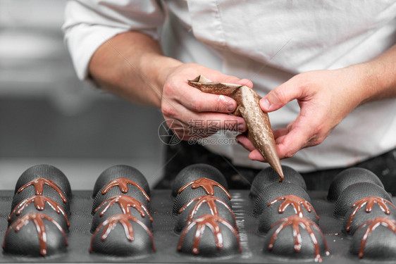 制作手工巧克力糖果商将液态黑巧克力倒入模具中特写行业排图片