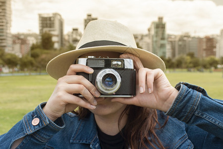 优质的阳光明媚早晨美丽西班牙裔女子戴着帽在公园中央用旧相机拍照户外蓝色的图片