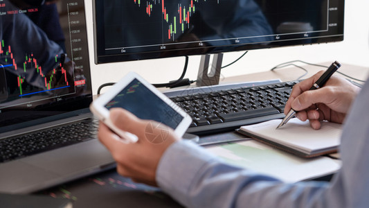 数字的信息外汇工作商人经纪或贸易商团队谈论股票市场多台计算机屏幕上的反面对交易金融图表数据分析进行投资的金融图表数据分析图片