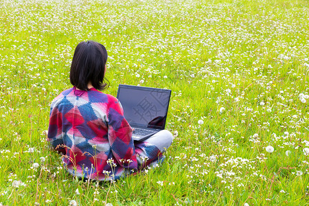 荷兰布谷鸟哥伦比亚女人坐在草地的笔记本电脑上花朵盛开青蒿图片