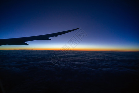 高的窗户空中飞机翼越云层的景象和日出时飞过陆地自然和旅行概念的奇妙天空在日出时飞过陆地自然和旅行的概念起床图片