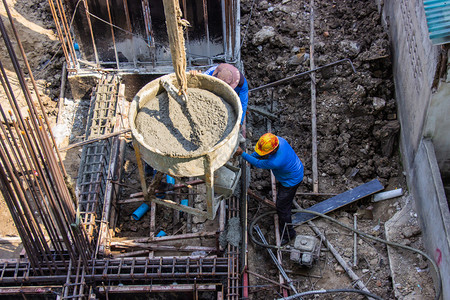 建造将水泥倒入地基的工人在建筑地的区进行成形工作式业图片