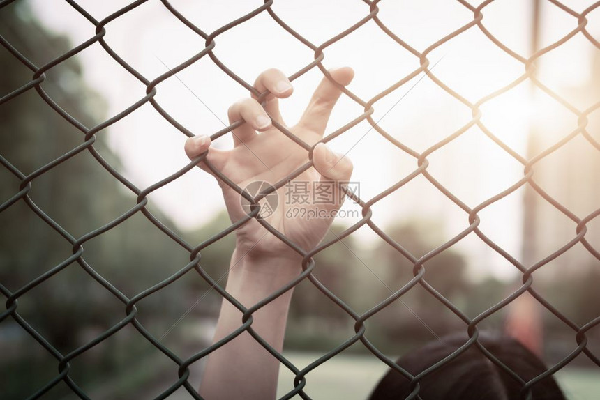 路障沮丧麻烦帮助和机会无望的妇女举手在连链栅栏上求救绝望图片