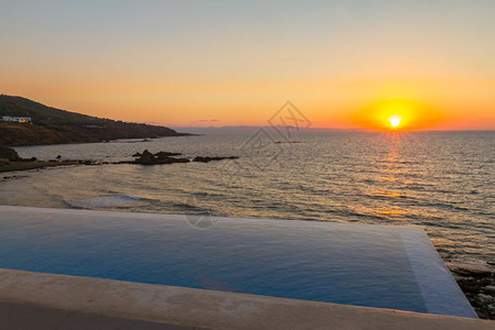 随着太阳在塞浦路斯岛帕福地区的Pomos下落游泳池俯视海洋浪美丽的春天图片