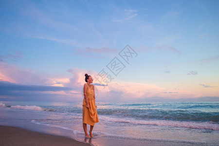 游客年轻美丽的女士在日落时海滩上放松女人躺在海滩上享受暑假看着海的夏天假期生活闲暇图片