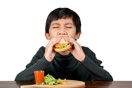 穿黑衬衫的亚洲可爱男孩吃着美味的汉堡包吃着白色背景脸晚餐卡路里图片