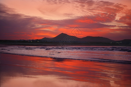 晚上异国情调美丽的兰萨罗特岛法马拉海滩的橙色日落图片