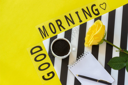卡片时髦的文本早上好一杯咖啡黄玫瑰和空笔记本用于黄色背景上时尚的黑白餐巾纸上文字简约风格的工作场所概念早上好平躺顶视图复制空间文图片