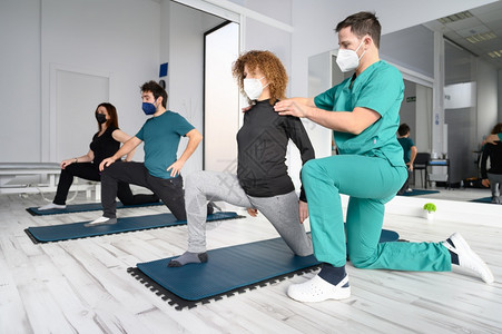 康复诊所物理治疗师协助下瑜伽垫上的一组人高质量照片康复诊所物理治疗师协助下瑜伽垫上的一组人子动机健身房图片