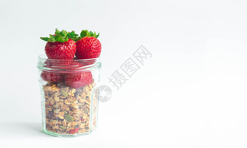 新鲜的草莓绿色的树叶头盖在健康的穆埃斯里粮仓顶上用干净的玻璃瓶装在白色背景有复制空间的白底玻璃杯子上标语甜点产品图片