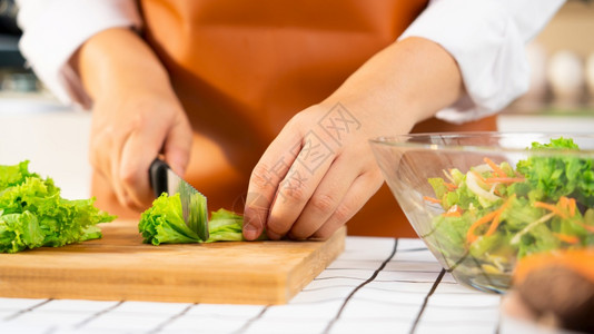 年轻的二十多岁亚洲年轻妇女正在准备健康食品蔬菜沙拉在轻厨房切开割板在家做饭和健康食品概念上刻物的成分正在制作健康食品蔬菜沙拉妻子图片