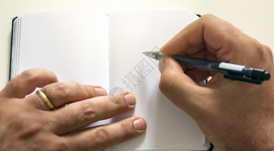 男手握一支圆点笔写在开放记本上的空白页创时灵感学生训练家图片