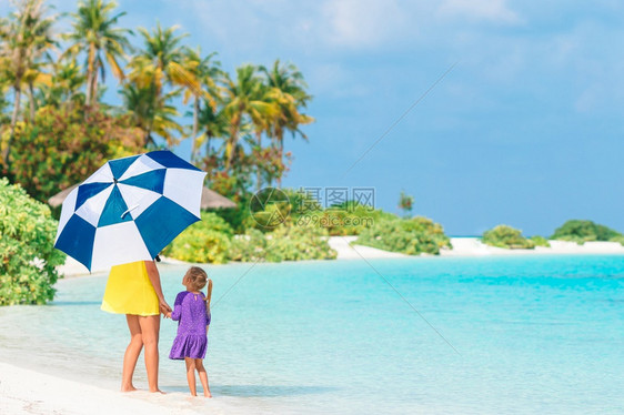 颜色夏天在热带海滩上母亲和小女孩的家庭配有雨伞的阳光美丽母亲和女儿在海滩上美丽妈和女儿户外图片