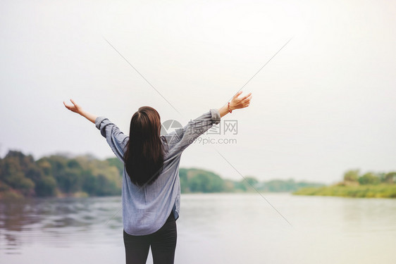 不寒而栗生命中未插塞的快乐妇女站在河水举起的手臂旁呼吸新鲜空气节假日和放松生活方式夏天快乐的图片