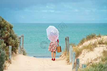 愉快户外在海滩上穿旧式礼服的漂亮女旅行者当地专注女快乐的图片