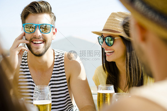 海滩朋友在沙酒吧玩得开心喝冷啤酒饮料太阳镜图片