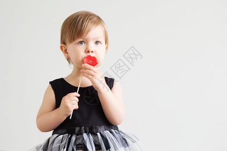 一个可爱的小女孩肖像带着可笑的红纸嘴唇在白色背景上漂亮的金发女郎情感图片