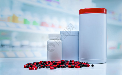 在药店Blank标签牌塑料药瓶的抗店柜台散布的红黑胶片药丸其维生素和添加剂的背景模糊在药店中展示架健康医疗的黑色图片