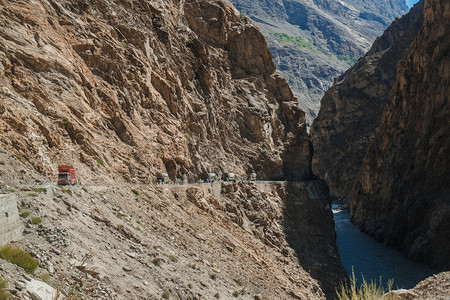 偏僻的巴基斯坦卡车乘坐沿悬崖附近山上危险的铺面公路通过巴基斯坦GilgitBaltistan的Karakoram高速公路运输货物图片