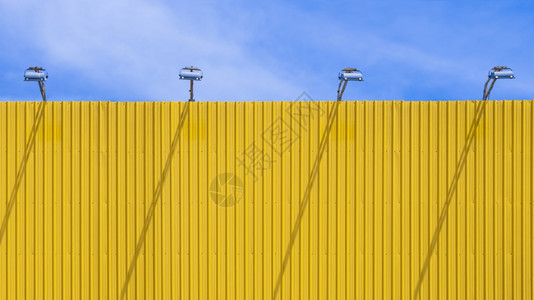 建筑学明日阳光下蓝天空背景的黄色户外空白告示板顶上四个聚光灯空的极简主义图片