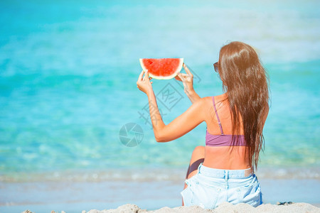 沙滩上举着西瓜的女士图片