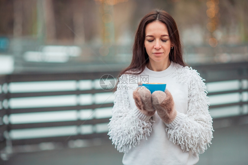 喝咖啡的快乐女孩在冬天白喝热咖啡用蓝杯的棉花糖在户外手握着一个蓝色杯子里的棉花糖女用白色和粉红棉花糖拿着白咖啡人们色的早晨图片