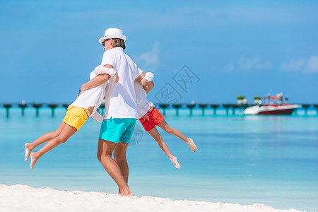 一种父母喜悦亲和孩子们一起在海滩上享受日落家庭假期快乐美丽的家庭在热带海滩度假图片