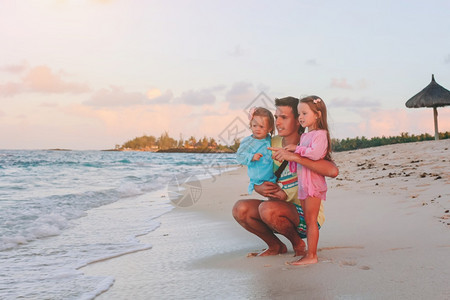 团结父亲和孩子们一起在海滩上享受日落家庭假期快乐美丽的家庭在热带海滩度假绿松石图片