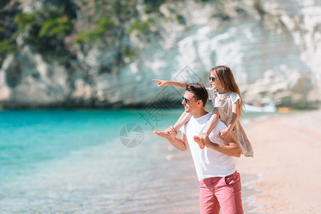 父亲在海滩上载着小女孩搭便车去海边度假的年轻家人玩得很开心年轻的热带图片