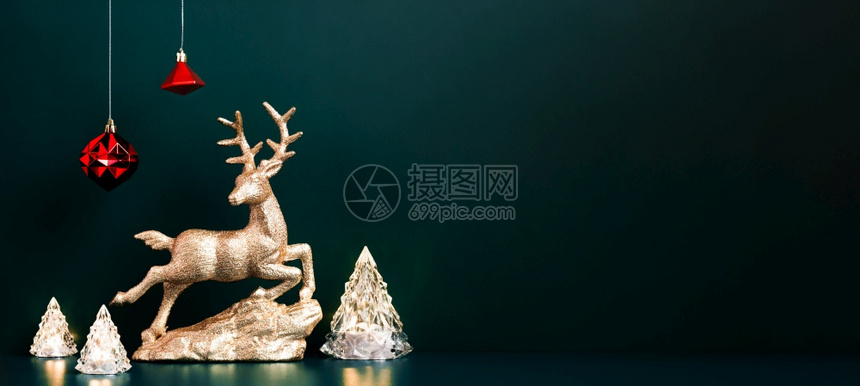 或者喜庆的横幅圣诞金驯鹿带有Xmas树灯的圣诞金驯鹿挂在深蓝绿色背景壁画模型上以展示设计或假日活动邀请卡和图片