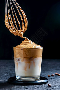 深色背景上加花冠的冰Dalgona咖啡时尚奶油鲜咖啡韩国寒冷夏季饮品韩国寒冷夏季饮品玻璃燕麦时髦的图片