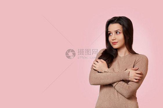 漂亮的一个年轻美丽亚洲黑发女孩肖像身着一件浅棕色夹克手举在胸前交叉粉红孤立的背景和复制空间上吸引人的图片