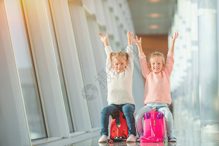 在大国际机场靠近窗户的机场适居少女和在机场的适居小女孩她们的行李等待登机候的假期大厅航班图片